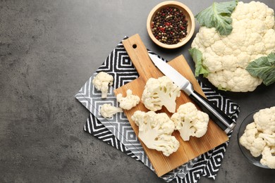 Photo of Fresh raw cauliflower florets, spices and knife on grey table, flat lay. Space for text