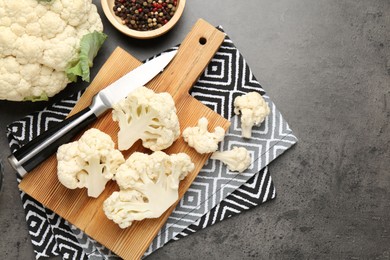 Photo of Fresh raw cauliflower florets, spices and knife on grey table, flat lay. Space for text