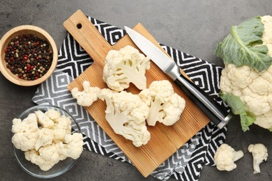 Photo of Fresh raw cauliflower florets, spices and knife on grey table, flat lay