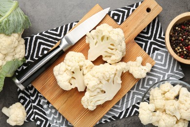 Photo of Fresh raw cauliflower florets, spices and knife on grey table, flat lay