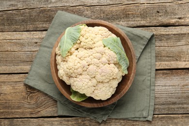 Photo of Fresh cauliflower with green leaves on wooden table, top view