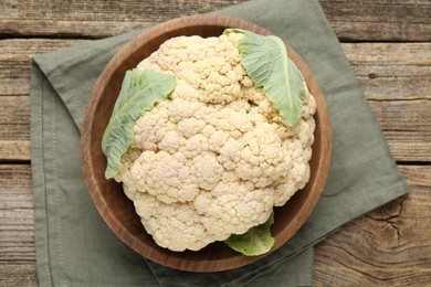 Photo of Fresh cauliflower with green leaves on wooden table, top view