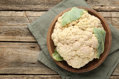 Photo of Fresh cauliflower with green leaves on wooden table, top view. Space for text