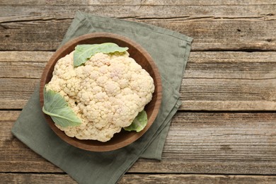Photo of Fresh cauliflower with green leaves on wooden table, top view. Space for text