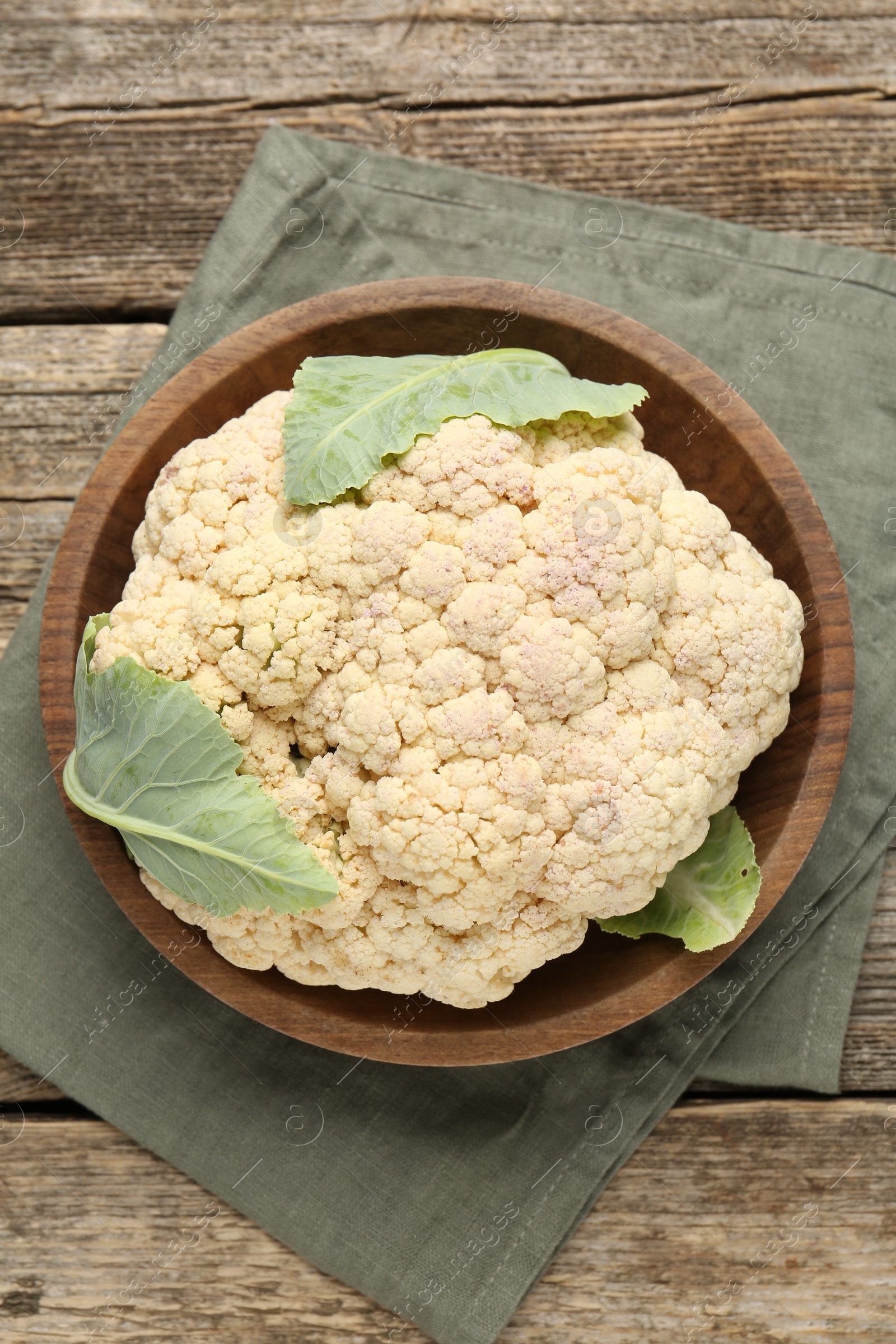 Photo of Fresh cauliflower with green leaves on wooden table, top view