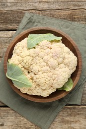 Photo of Fresh cauliflower with green leaves on wooden table, top view