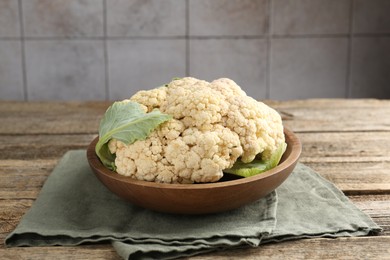 Photo of Fresh cauliflower with green leaves on wooden table, closeup