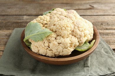Photo of Fresh cauliflower with green leaves on wooden table, closeup