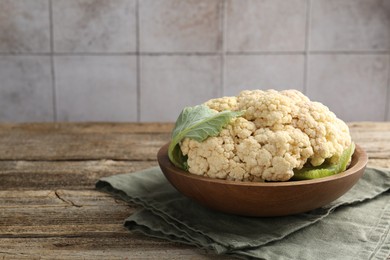 Photo of Fresh cauliflower with green leaves on wooden table, closeup. Space for text