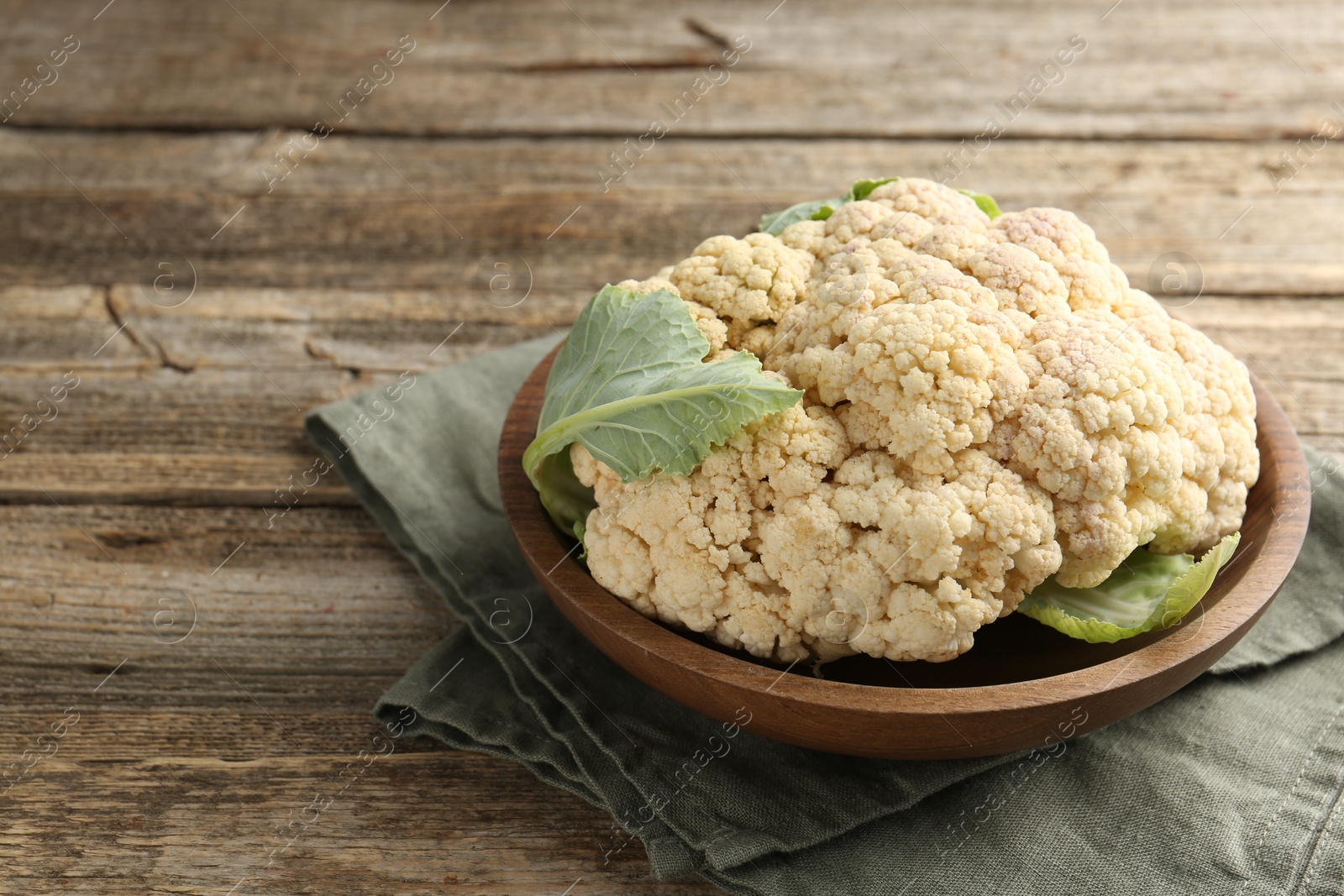 Fresh cauliflower with green leaves on wooden table, closeup. Space for text Photo of Fresh cauliflower with green leaves on wooden table, closeup. Space for text
