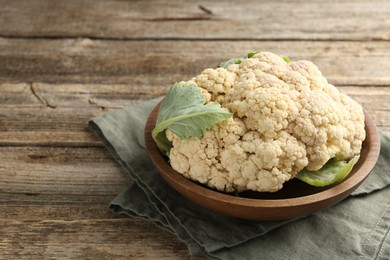 Photo of Fresh cauliflower with green leaves on wooden table, closeup. Space for text