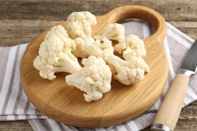 Photo of Fresh raw cauliflower florets and knife on wooden table, closeup
