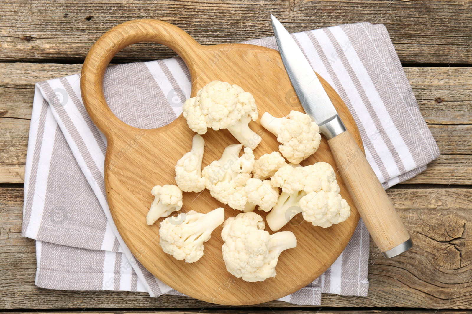 Photo of Fresh raw cauliflower florets and knife on wooden table, top view