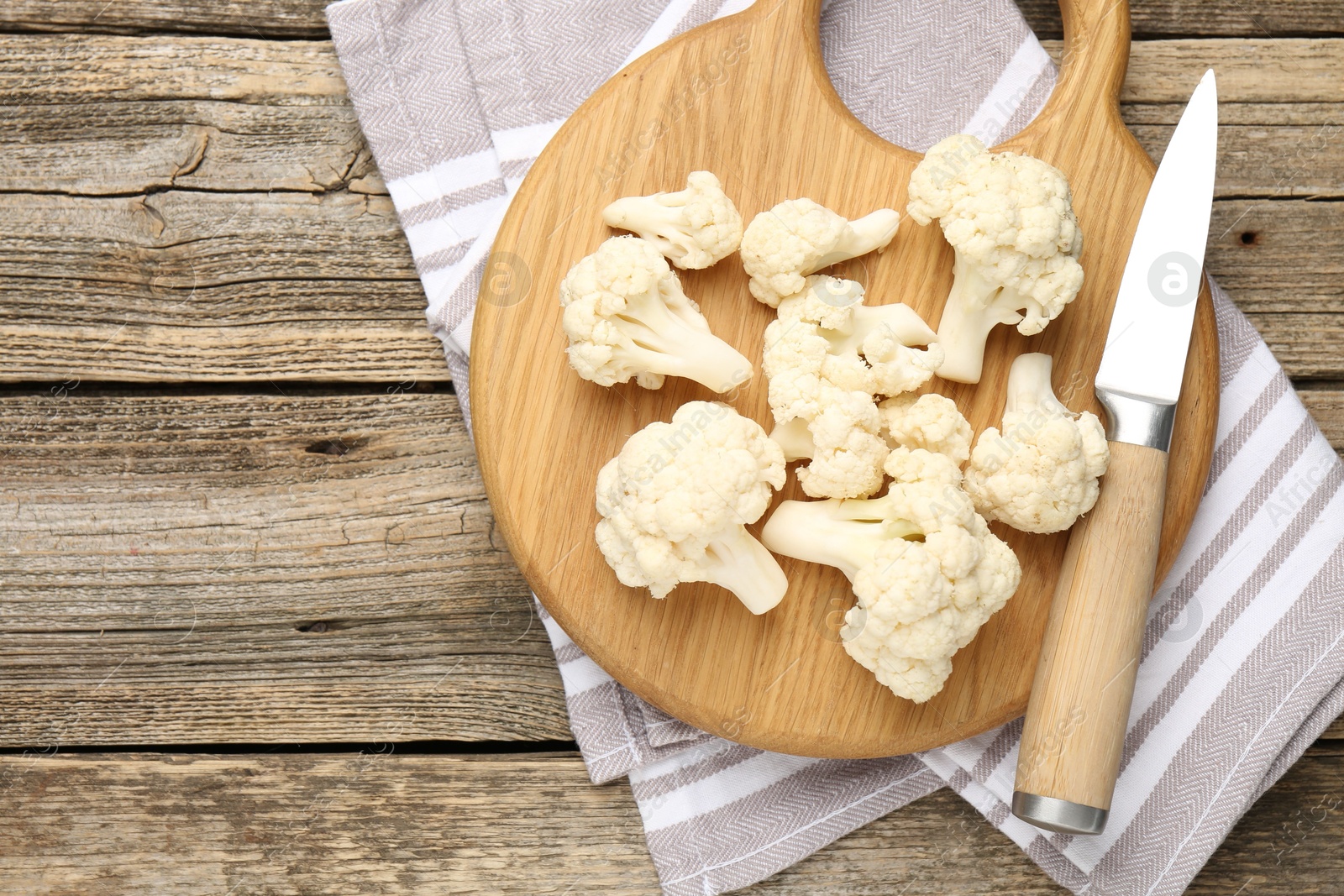 Fresh raw cauliflower florets and knife on wooden table, top view. Space for text Photo of Fresh raw cauliflower florets and knife on wooden table, top view. Space for text