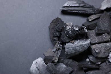 Photo of Pieces of black coals on grey background, top view. Space for text