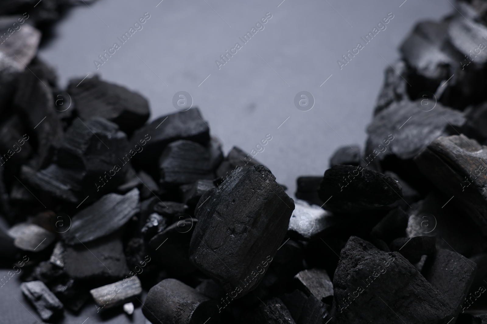Pieces of black coals on grey background, closeup. Space for text Photo of Pieces of black coals on grey background, closeup. Space for text