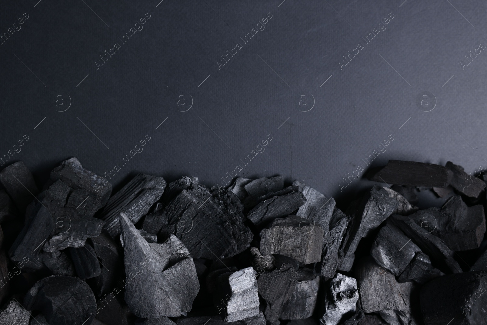 Pieces of black coals on grey background, top view. Space for text Photo of Pieces of black coals on grey background, top view. Space for text
