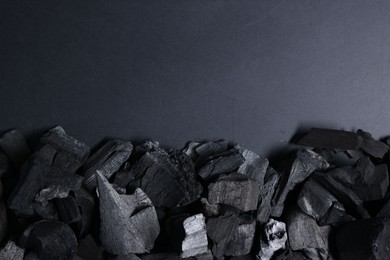 Photo of Pieces of black coals on grey background, top view. Space for text