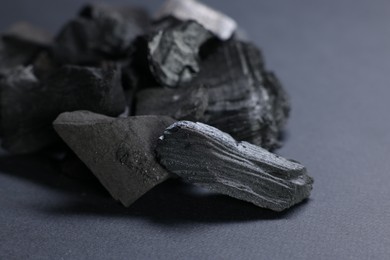 Photo of Pieces of black coals on grey table, closeup