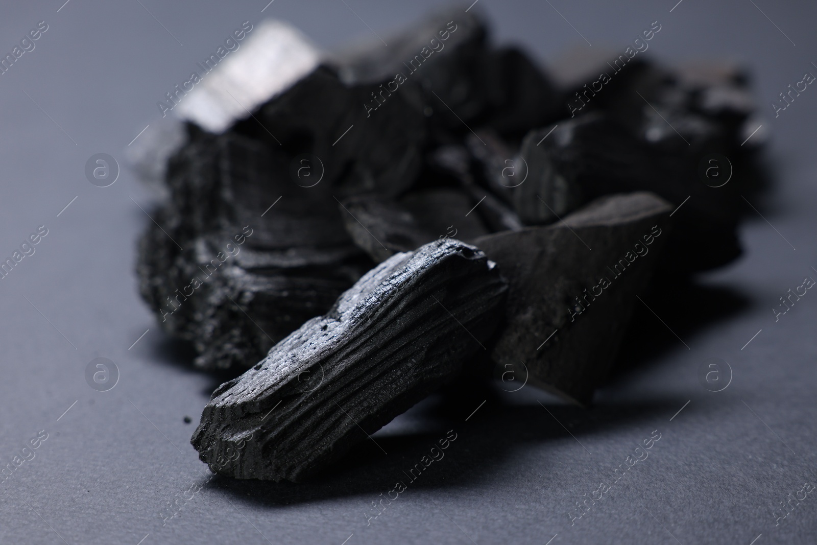 Pieces of black coals on grey table, closeup Photo of Pieces of black coals on grey table, closeup