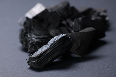 Photo of Pieces of black coals on grey table, closeup