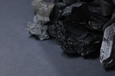 Photo of Pieces of black coals on grey table, closeup. Space for text