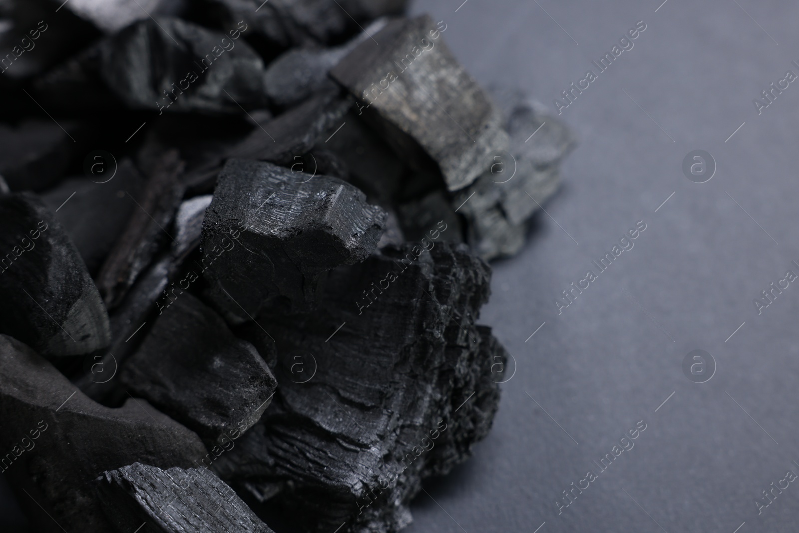Pieces of black coals on grey table, closeup. Space for text Photo of Pieces of black coals on grey table, closeup. Space for text