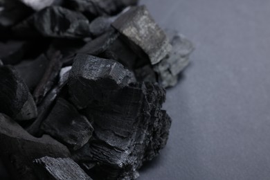 Photo of Pieces of black coals on grey table, closeup. Space for text