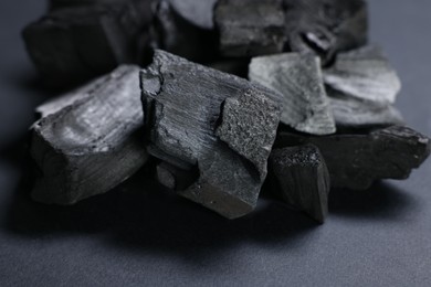 Photo of Pieces of black coals on grey table, closeup