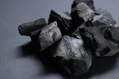 Photo of Pieces of black coals on grey table, closeup