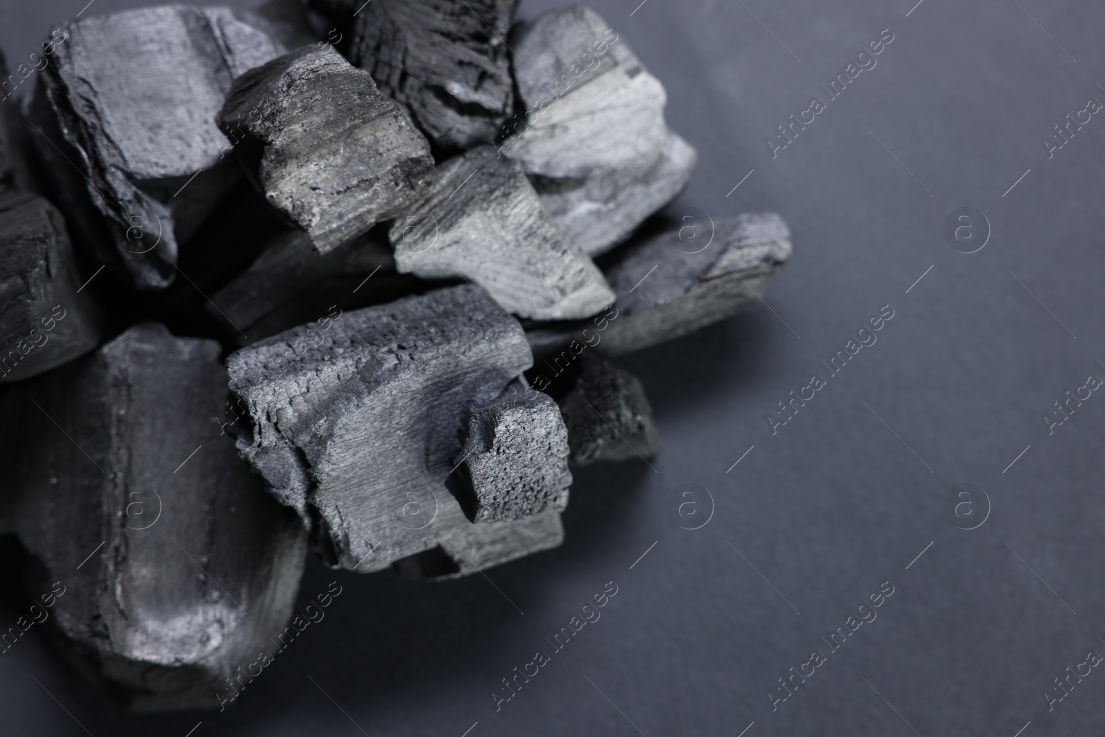 Pieces of black coals on grey table, closeup. Space for text Photo of Pieces of black coals on grey table, closeup. Space for text