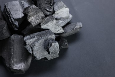 Photo of Pieces of black coals on grey table, closeup. Space for text