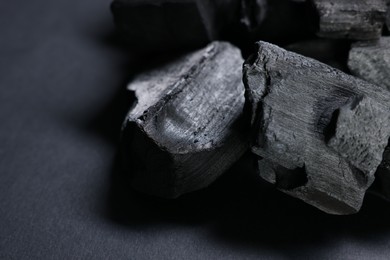 Photo of Pieces of black coals on grey table, closeup. Space for text