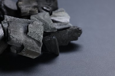 Photo of Pieces of black coals on grey table, closeup. Space for text
