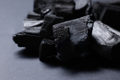 Photo of Pieces of black coals on grey table, closeup