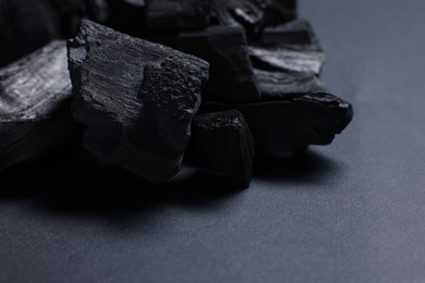Photo of Pieces of black coals on grey table, closeup