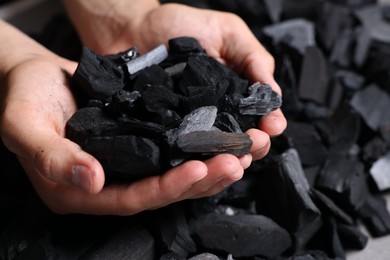 Photo of Man with black coals over pile, closeup