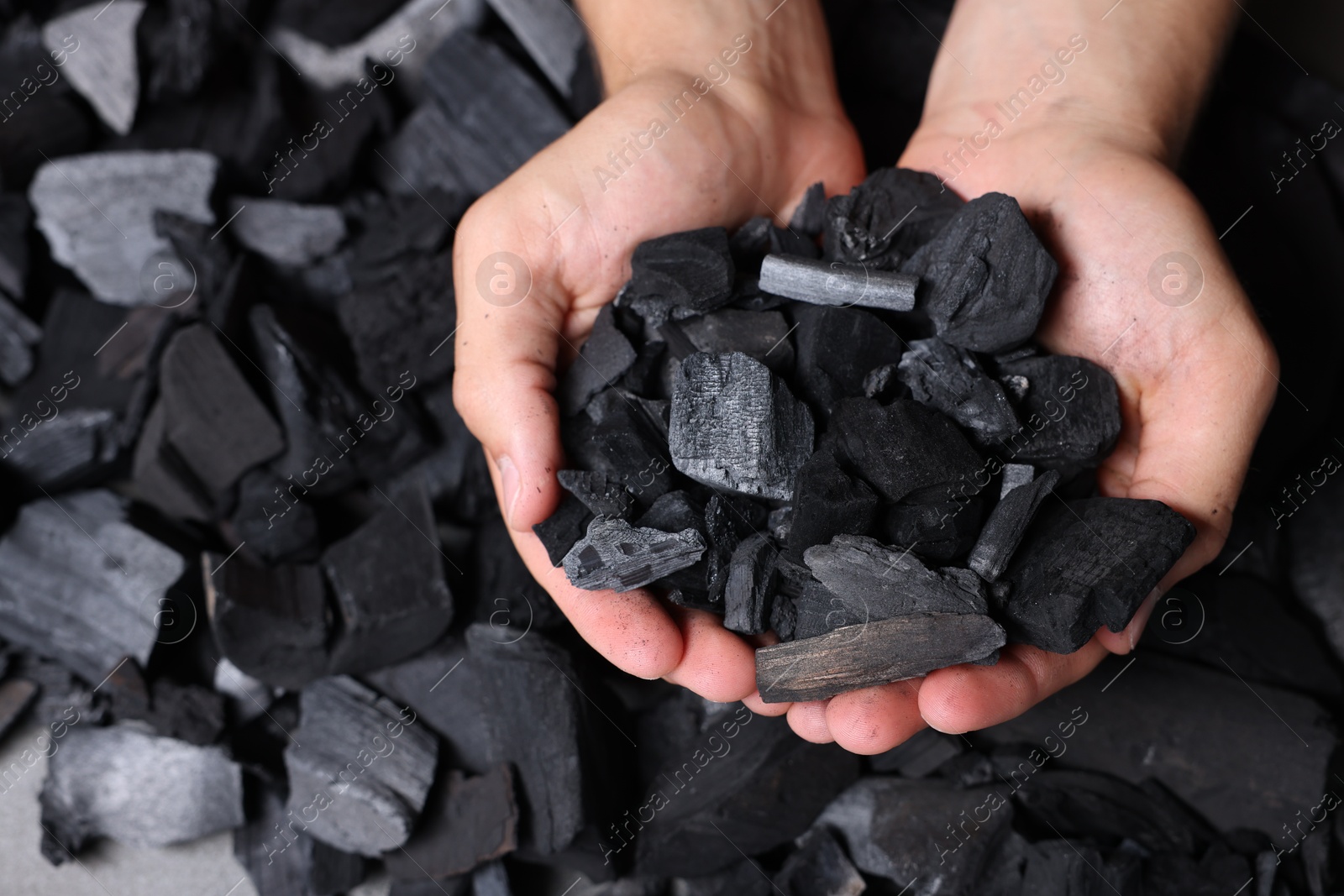 Man with black coals over pile, top view Photo of Man with black coals over pile, top view