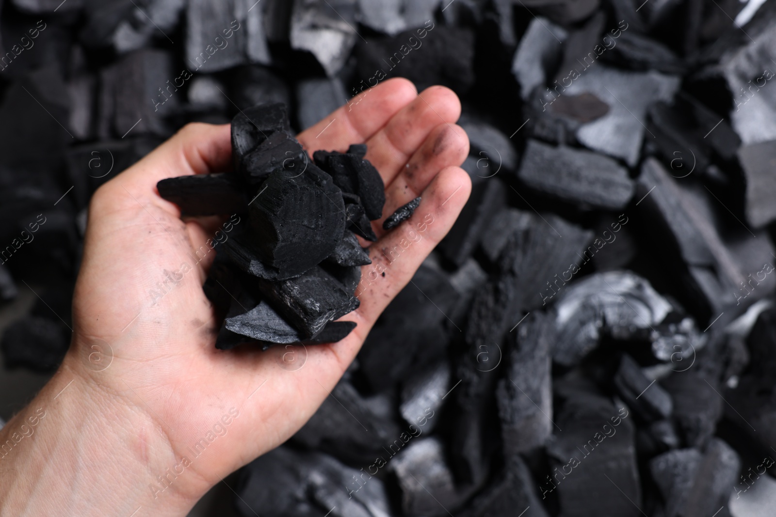 Man with black coals over pile, above view Photo of Man with black coals over pile, above view