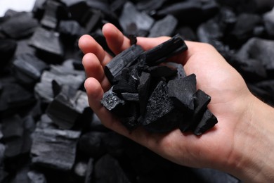 Photo of Man with black coals over pile, closeup