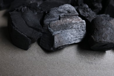 Photo of Pieces of black coals on grey table, closeup