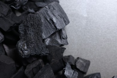 Photo of Pieces of black coals on grey table, top view. Space for text