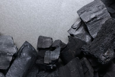 Photo of Pieces of black coals on grey table, top view. Space for text