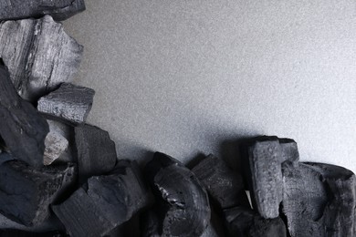 Photo of Pieces of black coals on grey table, top view. Space for text
