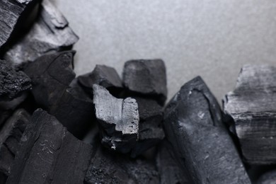 Photo of Pieces of black coals on grey table, top view