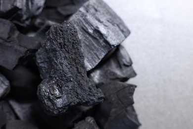 Photo of Pieces of black coals on grey table, closeup. Space for text