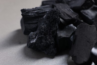 Photo of Pieces of black coals on grey table, closeup