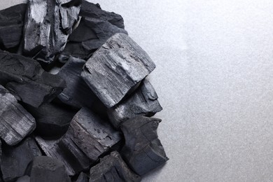 Photo of Pieces of black coals on grey table, top view. Space for text