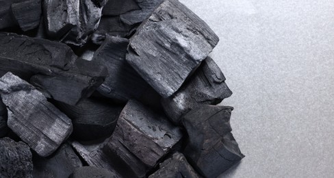 Photo of Pieces of black coals on grey table, top view. Space for text