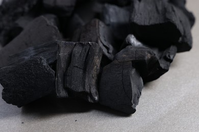 Photo of Pieces of black coals on grey table, closeup